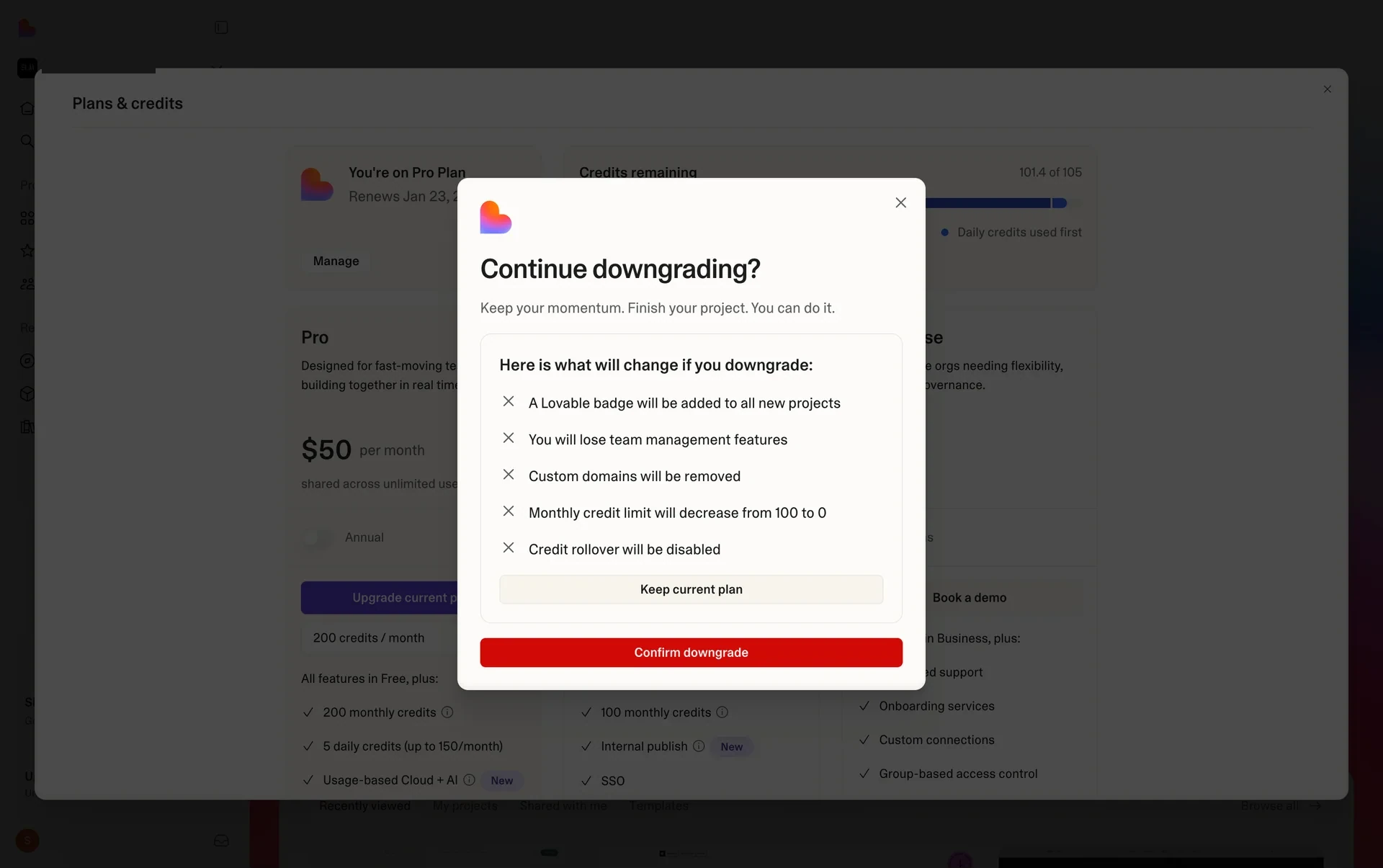 Lovable "Continue downgrading?" screen headed "Here is what will change if you downgrade:" listing a Lovable badge added to new projects, loss of team management features, custom domains removed, monthly credit limit decreasing, and credit rollover disabled, with a Keep current plan button and a red Confirm downgrade button
