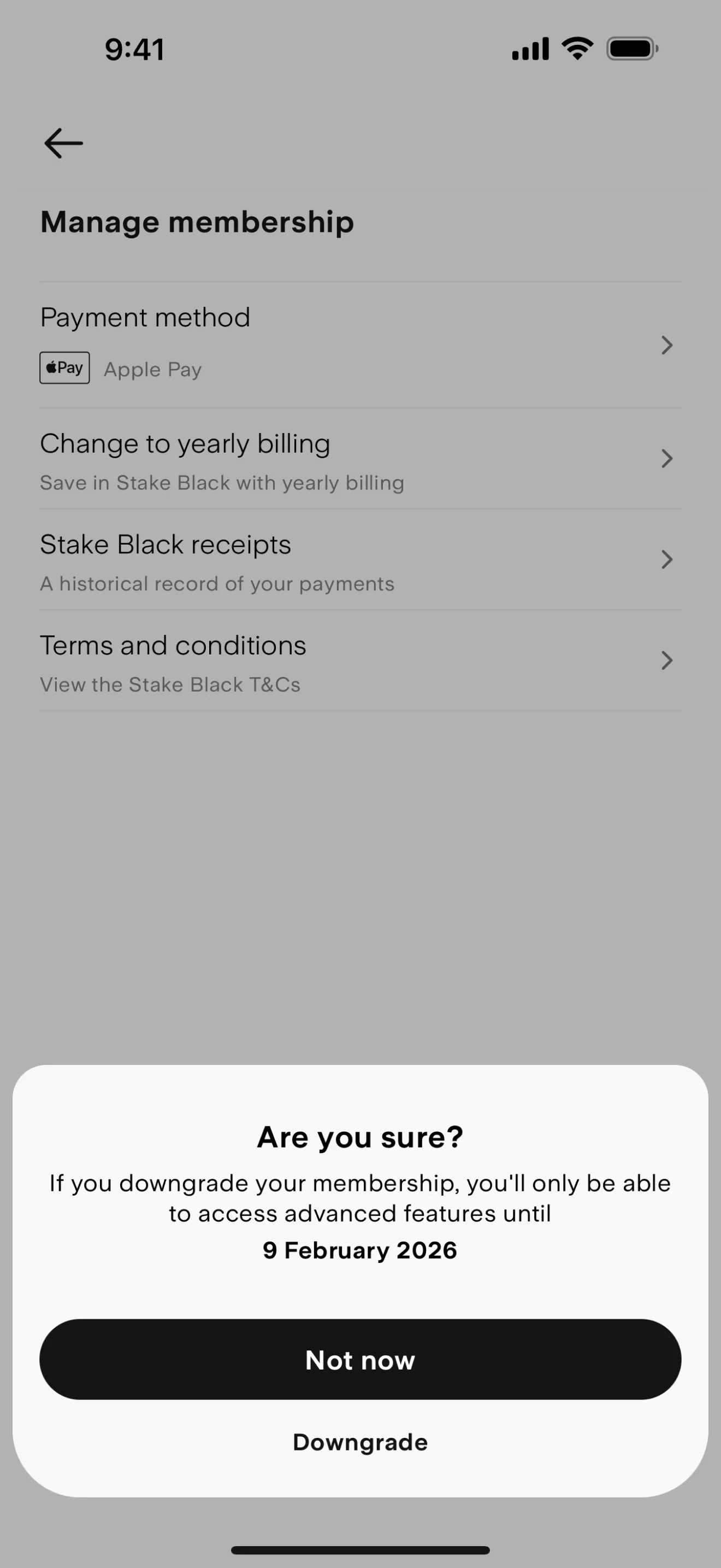 Stake Are you sure confirmation sheet over Manage membership stating advanced features last until 9 February 2026, with a large black Not now button above a plain Downgrade text button; payment method shows Apple Pay